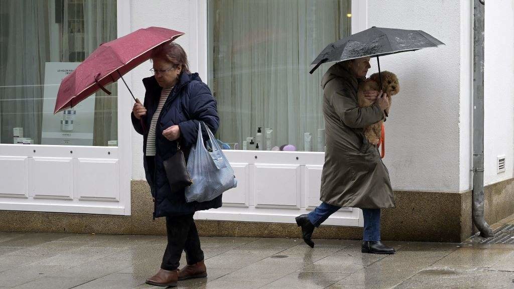 Dúas persoas refúxianse do vento e da chuvia baixo o paraugas. (Foto: M. Dylan / Europa Press).