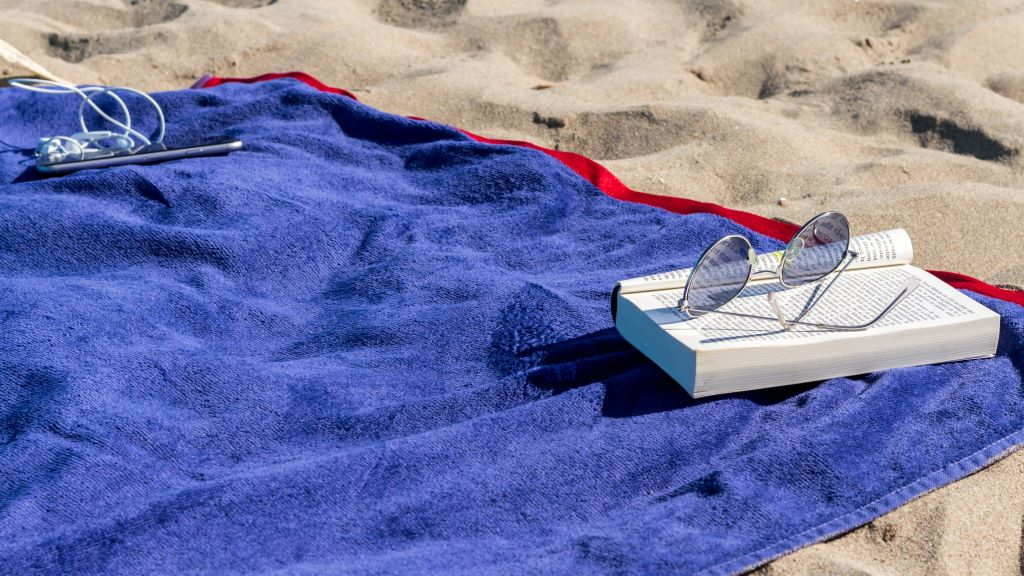Un libro sobre unha toalla azul tendida na praia. (Foto: Daniel).
