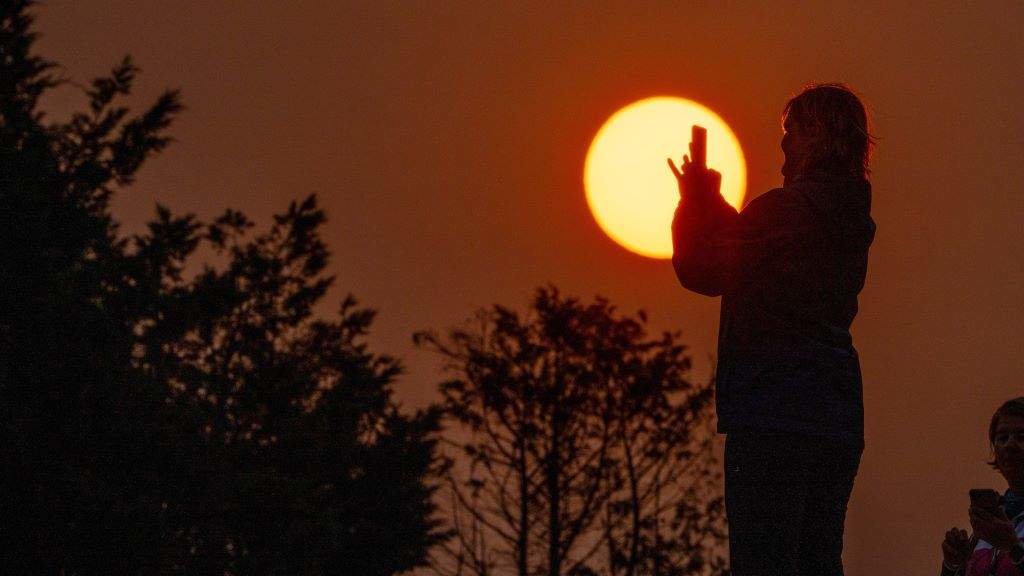 Un muller captura a Superlúa, esta quinta feira no Monte do Gozo, en Compostela. (Foto: Álvaro Ballesteros / Europa Press)